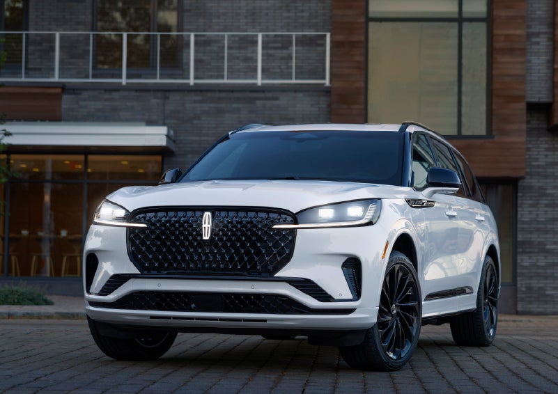 A 2026 Lincoln Aviator® Reserve model is shown with the available Jet Appearance Package parked near a restaurant. | LaFontaine Lincoln Grand Blanc in Flint MI