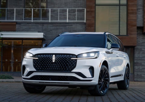 A 2026 Lincoln Aviator® Reserve model is shown with the available Jet Appearance Package parked near a restaurant. | LaFontaine Lincoln Grand Blanc in Flint MI