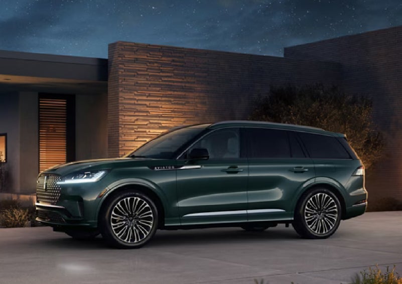 A green 2027 Lincoln Aviator® SUV is parked outside a contemporary home. | LaFontaine Lincoln Grand Blanc in Flint MI