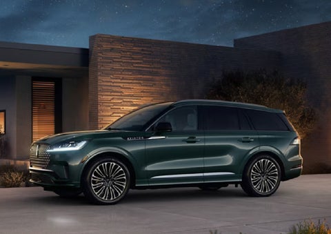 A green 2027 Lincoln Aviator® SUV is parked outside a contemporary home. | LaFontaine Lincoln Grand Blanc in Flint MI