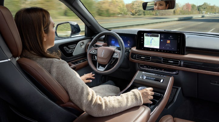 A 2027 Lincoln Aviator® SUV is being driven hands-free on a highway lined with trees. | LaFontaine Lincoln Grand Blanc in Flint MI