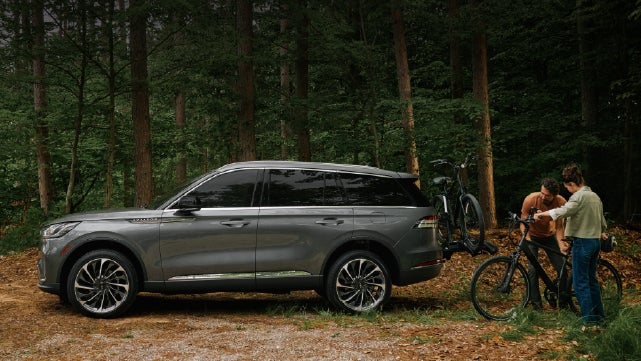 A father and son load e-bikes on a bike rack attached to a 2027 Lincoln Aviator® SUV. | LaFontaine Lincoln Grand Blanc in Flint MI