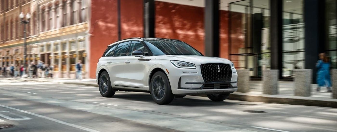 White 2023 Lincoln Corsair driving down a city street.