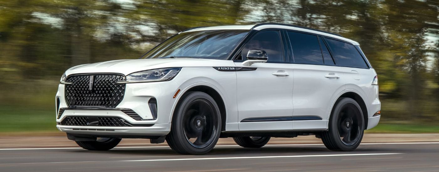 White 2026 Lincoln Aviator from the side driving on a paved road.