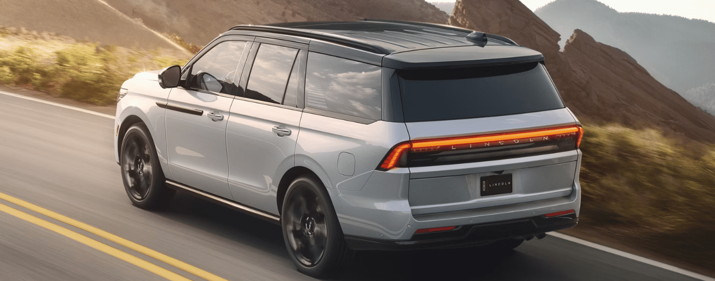 Blue 2027 Lincoln Navigator driving along a mountainous road