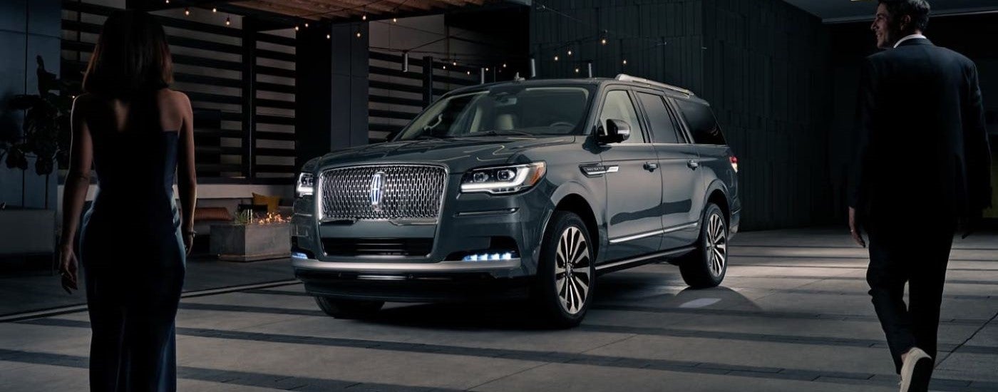 People walking towards a black 2023 Lincoln Navigator parked near a Lincoln dealer near Brighton.