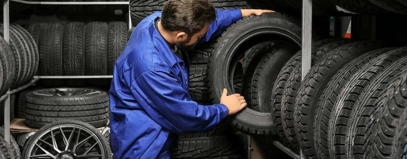 Mechanic stacking tires on a rack.